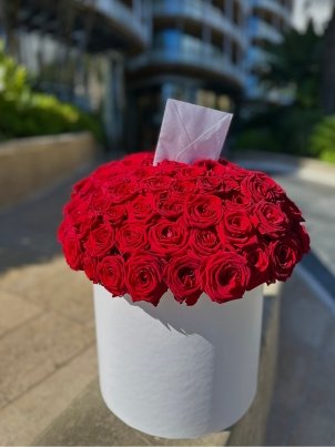 Элегантная круглая коробка, наполненная яркими красными розами размера L.