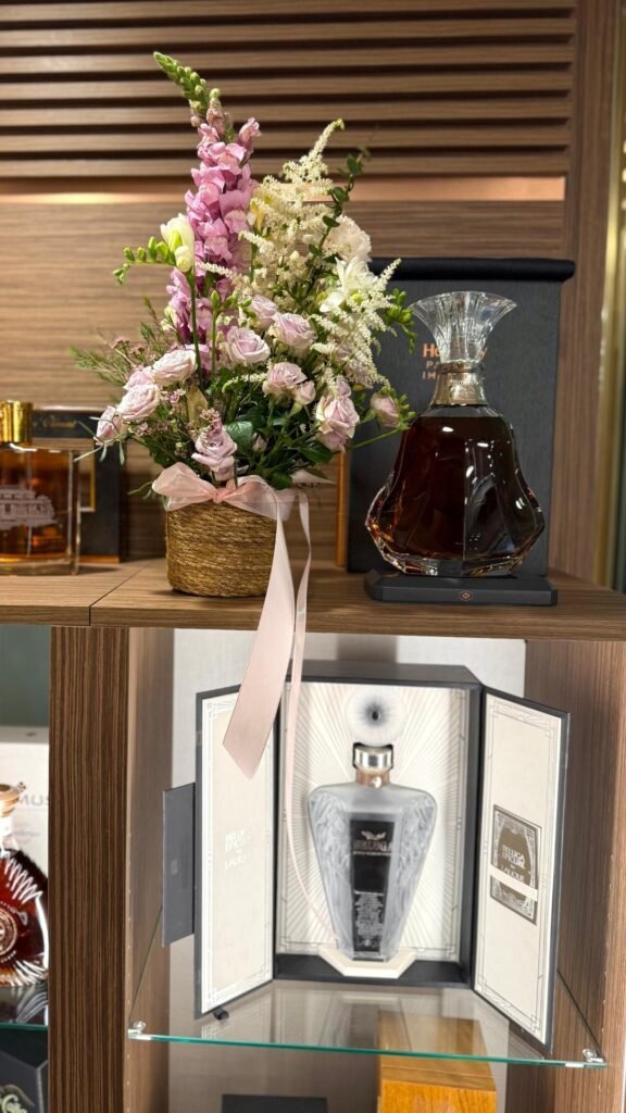 На полке расположены цветы, элитный алкоголь и стильный декор.