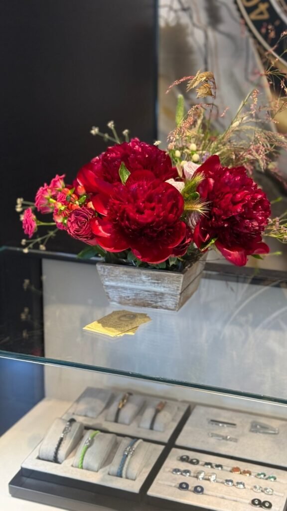 Букет красных цветов в деревянной вазе на фоне ювелирных изделий.