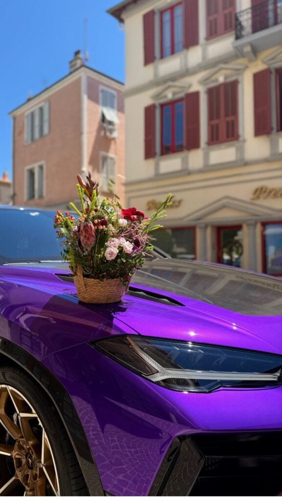 Фиолетовый автомобиль украшен букетом цветов на капоте под ярким солнцем.