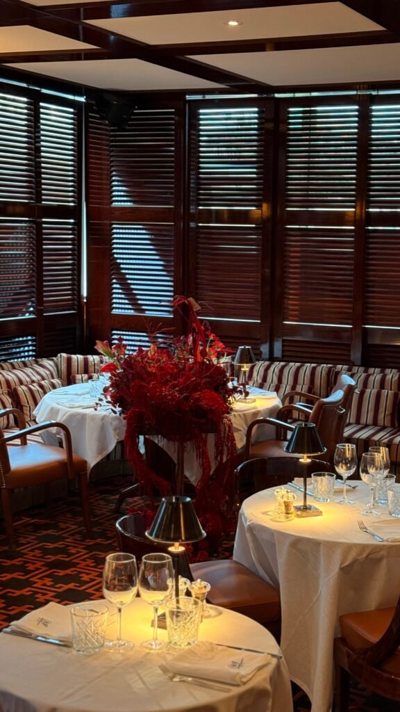 Элегантный ресторан с уютными столиками и стильным оформлением на фоне деревянных жалюзи.