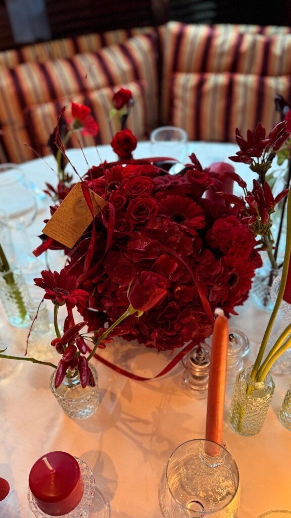 Красивый букет из красных цветов и свечи на праздничном столе.