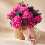 Close-up of vibrant neon-pink peonies and fresh blue thistle